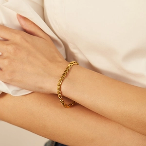 Detailed view of hollow heart-shaped gold bracelet links on a model's wrist