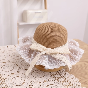 Detailed close-up of straw sun hat with elegant white lace embroidery and ribbon bow