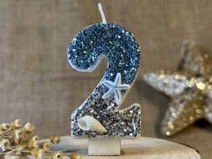Detail of ocean-themed birthday candle number 2 with blue glitter, seashell and starfish