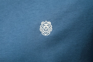 Macro view of white lion embroidery on dark blue premium cotton v-neck t-shirt