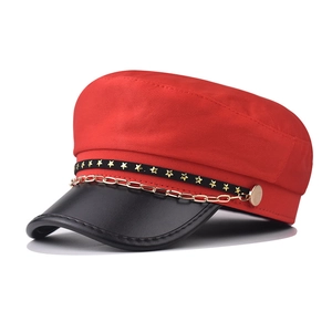Detail of red and black military cap with golden chain and star studs decoration