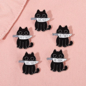 Close-up of black cat enamel pins with knives and gender pronouns on pink denim