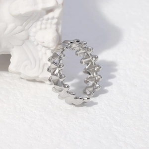 Detail of silver wavy geometric stainless steel open ring next to white artistic sculpture