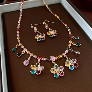 Close-up of vintage gold necklace and earrings set with colorful gemstones in a brown box