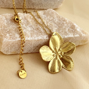 Elegant gold stainless steel necklace with textured 5-petal flower pendant on silk fabric