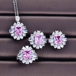Macro shot of silver jewelry set featuring rectangular pink gemstones and halo diamonds