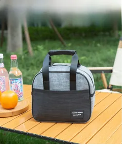 Insulated lunch bag on outdoor wooden table featuring grey cationic fabric and top handles