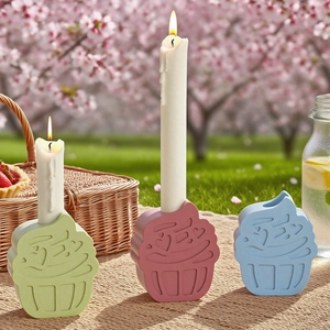 Three colorful cupcake resin candle holders with white candles in a picnic setting