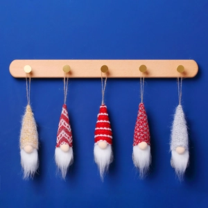 Five wool dwarf plush ornaments in red and gold colors hanging on a wooden rack