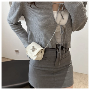 Detail of white saddle bag featuring a 3D metal butterfly and silver chain strap