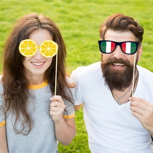 Happy couple using funny lemon and Italian flag glasses photo booth props outdoors