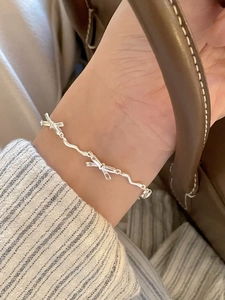 Detail of elegant S925 silver bow bracelet on wrist with refined wavy chain design