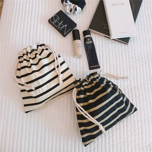 Flat lay of striped linen drawstring bags with thick cotton cords on white fabric