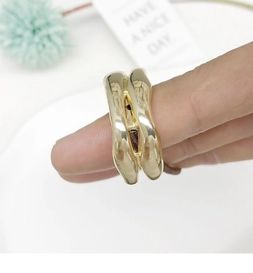 Macro view of a gold irregular wavy ring with liquid metal texture on finger