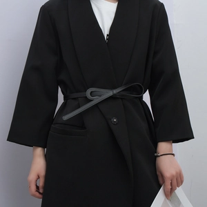 Detail of slim black leather belt tied in a bow knot over a professional blazer