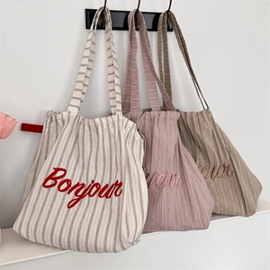 Detailed view of striped canvas tote bags with Bonjour embroidery and drawstring closure