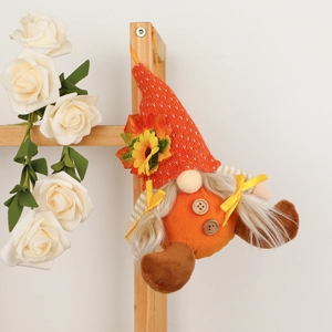 Dettaglio di gnomo autunnale con cappello a girasole appeso a uno scaffale in legno