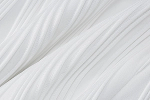 Close-up of white pleated knit fabric showing detailed vertical ribbed texture and soft material