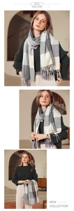 Detail view showing gray and white plaid pashmina scarf texture and tassel trim details