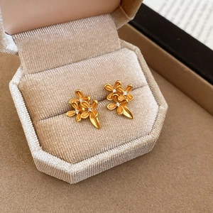 Macro shot of 24K gold plated flower stud earrings with zircons in a velvet jewelry box