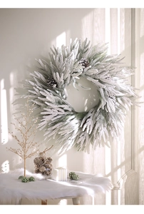 Close-up of white-green Christmas wreath with frost effect and pine cones on a wall