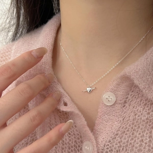 Close-up of a silver heart-shaped planet pendant on a delicate chain necklace