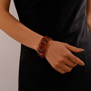 Detail of amber geometric resin bangle showing translucent triangular cut facets on wrist
