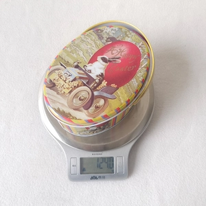 Tinplate Easter egg storage box showing a net weight of 124.0g on a digital scale
