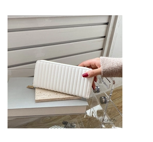 Close-up of a white quilted PU leather long wallet with vertical stitching and gold zipper