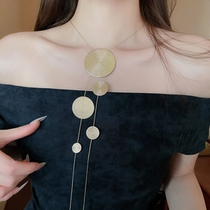 Detail of golden geometric circular pendant with spiral texture on long tassel necklace