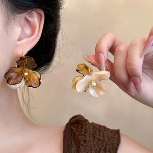 Detail of amber and cream resin flower earrings with gold accents on model