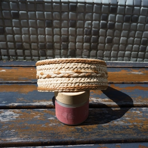 Close-up of beige and brown woven raffia headband showing intricate texture on bottle