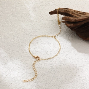 Detailed view of elegant gold chain bracelet with white pearls and adjustable lobster clasp