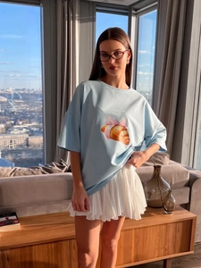 Κοντινό πλάνο γαλάζιο βαμβακερό T-shirt με τύπωμα κρουασάν και λευκή πλισέ φούστα