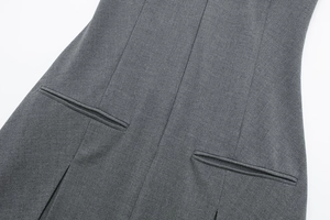 Detail van de taille-stiksels en paspelzakken op een grijze polo-jurk van fijne stof