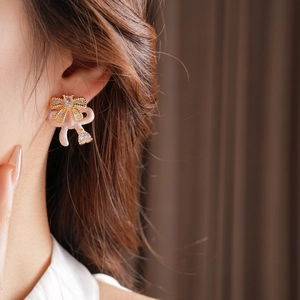 Close-up of pink bow earrings with sparkling heart-shaped zircons on a model