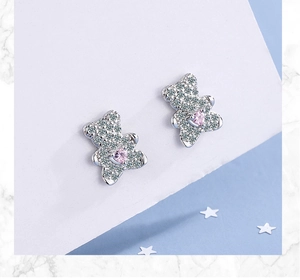 Macro shot of silver teddy bear earrings with white pavé zircons and pink heart stones