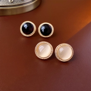 Vintage round cat-eye stone stud earrings with gold twisted borders on brown leather