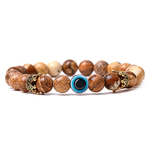 Close-up of map stone beads bracelet with evil eye charm and golden crown accents