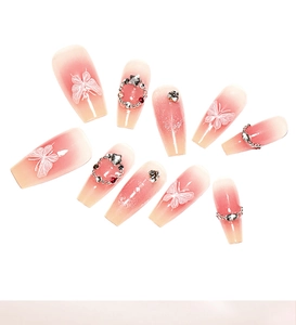 Detail von Coffin-Nägeln mit Blush-Verlauf, Schmetterlingsdesign und glitzernden Strasssteinen