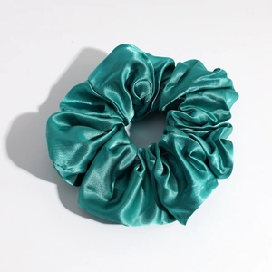 Detailed close-up of emerald green satin scrunchie showing smooth silk texture and pleats