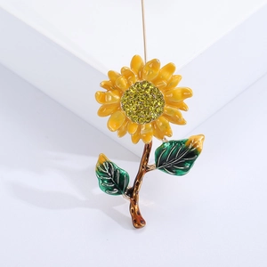 Detail of yellow enamel sunflower brooch with sparkling rhinestones on white base