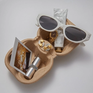 Eco-friendly brown pulp jewelry tray showcasing watches and personal items in a top view