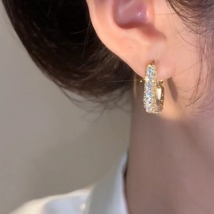 Close-up of elegant gold plated zircon square hoop earrings on model's ear