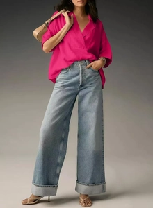 Detail of rose red V-neck short sleeve shirt paired with light blue wide leg cuffed jeans