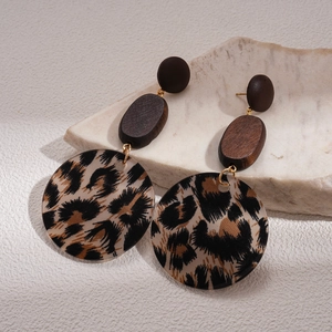 Detail of wooden and leopard print acrylic earrings on a white stone base