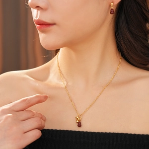 Close-up of 18k gold plated red gourd pendant necklace and earrings on model neck
