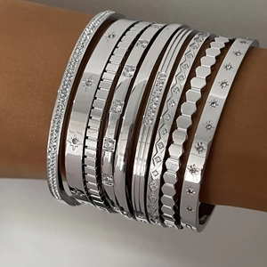 Close-up of nine silver stainless steel bracelets featuring star engraving and zircon inlay