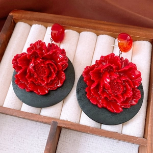 Macro detail of red vintage flower earrings with glossy petals in a wooden jewelry box