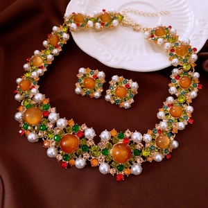 Makroaufnahme von Vintage-Schmuckset mit Perlen und Bernsteinkristallen auf braunem Stoff